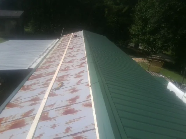 Old rusted panels beside newly installed green metal roofing — Wind Damage Roof Repair by Roofing Brothers in Grottoes