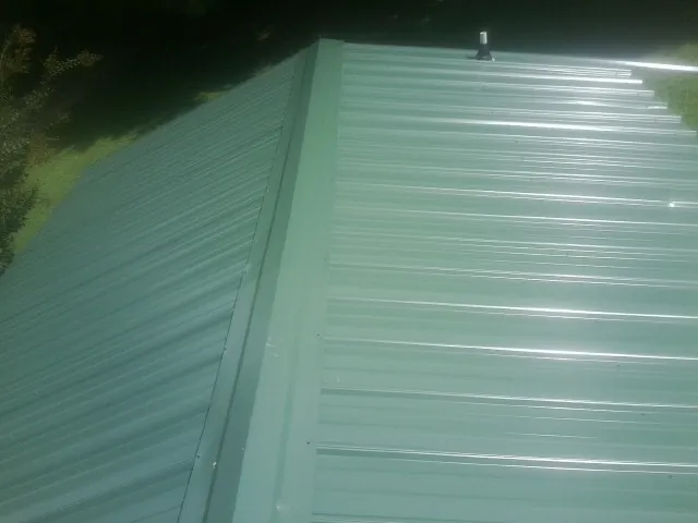 New green metal panels meeting at the ridge of a roof — Flat Roof Repair work by our crew in Grottoes