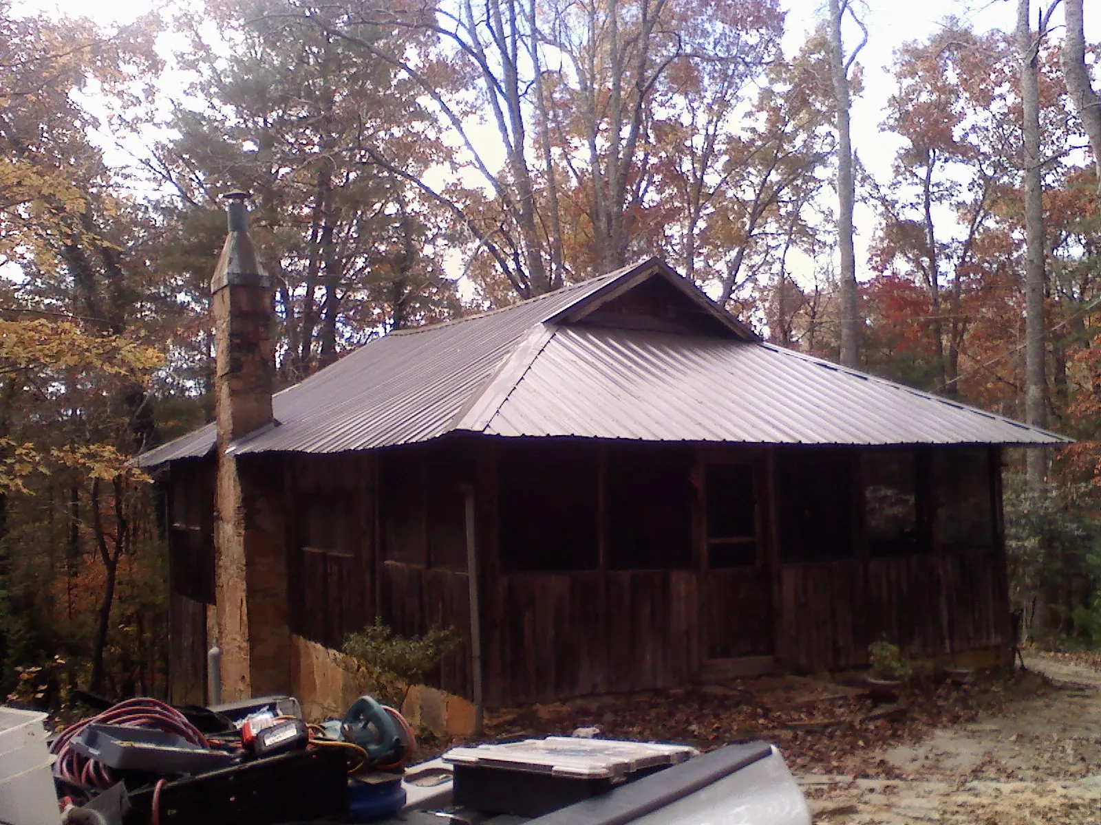 Brown metal hip roof on an old cabin with a stone chimney in Grottoes