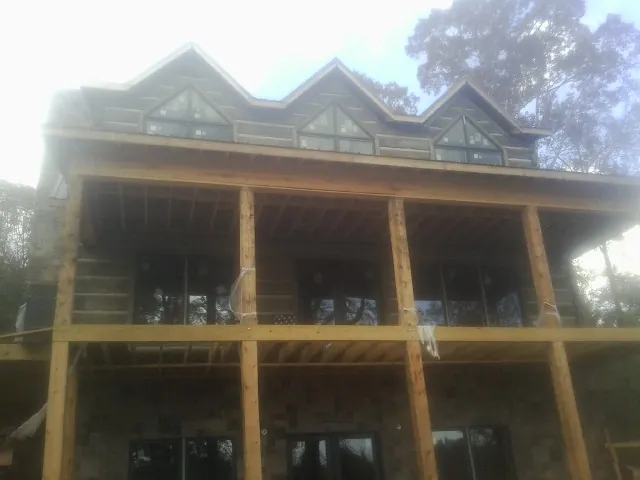 Dormers and porch framing on a large log home under construction — Roof Coating work by our crew in Grottoes
