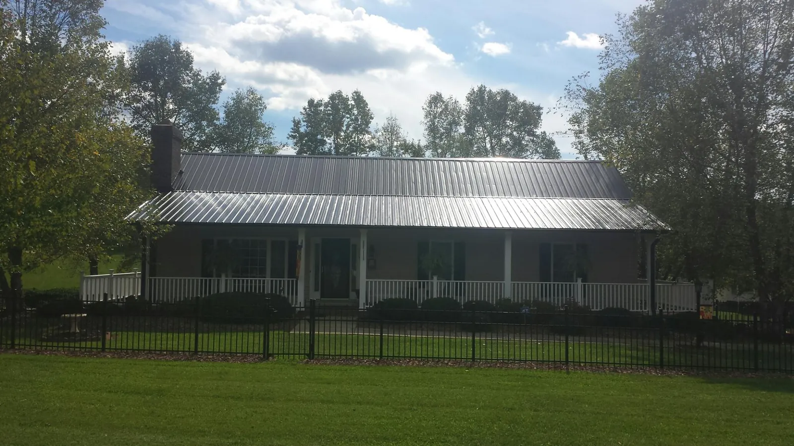 Gray metal roof on a brick ranch with a full width front porch — Gutter Guard Installation work by our crew in Grottoes