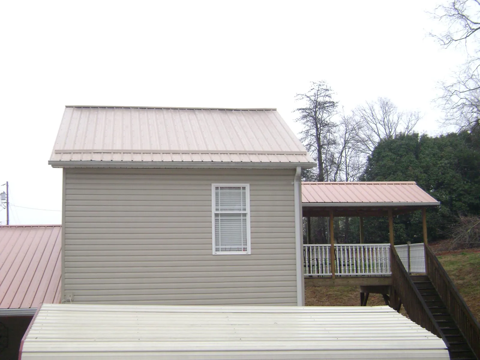 Tan metal roofs on a two story addition and attached porch, from a Roof Replacement job in Grottoes