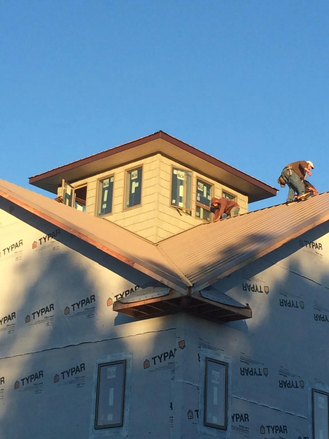 Roofers working around a rooftop cupola on a new metal roof at sunset — Roof Waterproofing in Grottoes by Roofing Brothers
